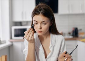 woman-in-kitchen-doing-makeup-with-eyeliner-pencil-in-hand-photo