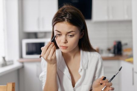 woman-in-kitchen-doing-makeup-with-eyeliner-pencil-in-hand-photo
