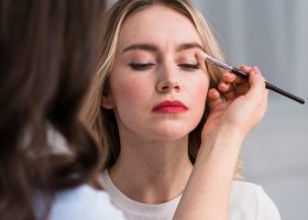 young-woman-applying-makeup-by-v